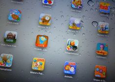 an ipad with many different app icons displayed on the screen, and water droplets all over it