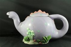 a ceramic teapot with green plants and rocks on the outside, sitting on a black surface