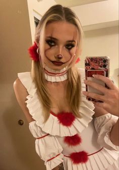 a woman with makeup on taking a selfie in the mirror while wearing a costume