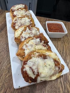 some food is laying out on a white plate next to a small bowl of sauce