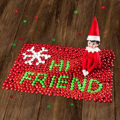 an elf is sitting on top of a christmas sign made out of candy balls with the words happy new year spelled in green and red letters