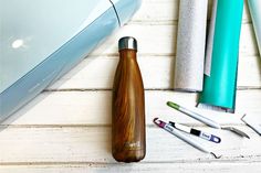 various office supplies including pens, scissors and an apple laptop on a white wooden surface