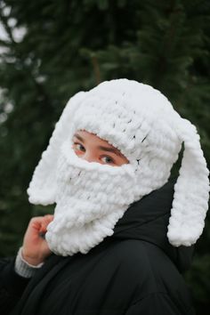 a woman wearing a white crocheted hat and scarf with ears on her head