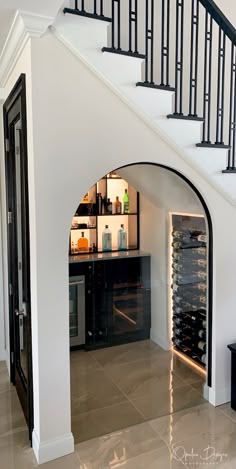 a wine cellar under the stairs in a house with white walls and black railings