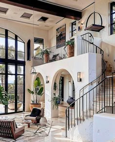 a living room filled with lots of furniture next to large windows and a stair case