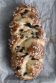 two loaves of bread with raisins and cheese on top sitting on a piece of wax paper