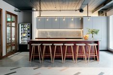 a kitchen with bar stools next to it and an open refrigerator in the background