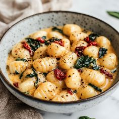 a bowl filled with pasta and spinach on top of a white table cloth next to a napkin