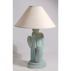 a ceramic cactus lamp sitting on top of a white table next to a light shade