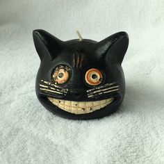 a black cat mask with orange eyes on a white background and a toothpick in the mouth