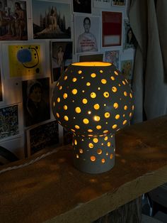 a lit up vase sitting on top of a wooden table next to pictures and posters