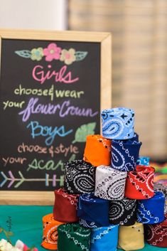 a pile of colorful ties sitting on top of a table next to a chalkboard