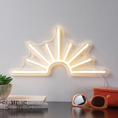 a white light sitting on top of a table next to a potted plant and sunglasses