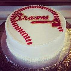 a cake that is sitting on a plate with the word braves written in gold and red