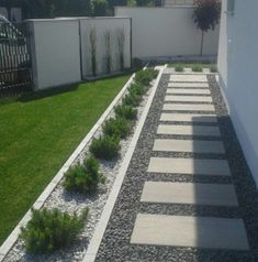 a small garden with grass and rocks in the middle, along side a white fence