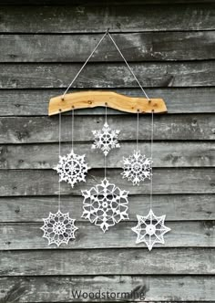 snowflakes are hanging from a wooden hanger on the side of a building