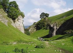 some people are walking in the grass near rocks