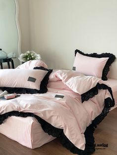 a bed with pink sheets and black ruffles on the bottom is shown in front of a mirror