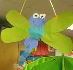 a paper cut out of a dragon hanging from a ceiling in an office area with green bins