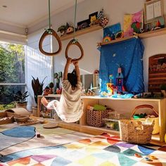 a woman is hanging on two rings in her living room with toys and other items