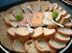 a platter filled with sandwiches and dips on top of a black countertop