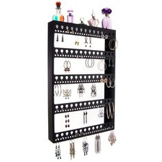 a black and white wall mounted jewelry rack with multiple pairs of earrings hanging on it