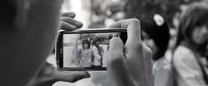 a person taking a photo with their cell phone in front of other people on the street