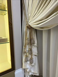 a curtain with tassels hanging from it in front of a glass display case