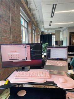 two laptops and a desktop computer on a desk in an office setting with brick walls