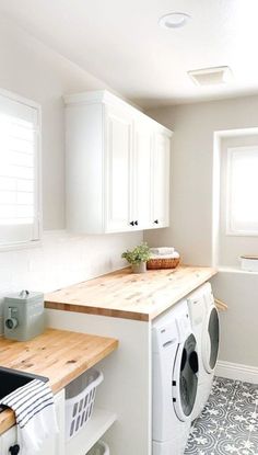 a washer and dryer in a white kitchen with wood counter tops on the counters