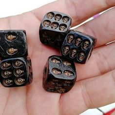 a hand holding four black dices with skulls on them