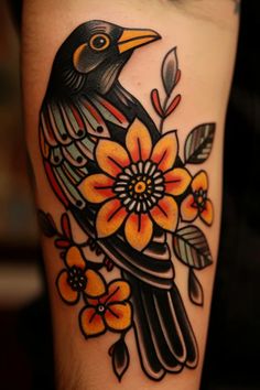 a black bird with orange and yellow flowers on it's leg is sitting on the arm