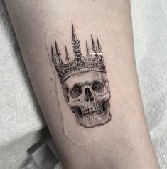 a skull with a crown on it's head is seen in this tattoo design