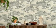 a fish wallpaper in a living room next to a potted plant and books