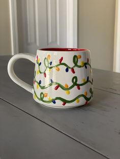 a coffee mug with christmas lights painted on the outside and inside is sitting on a table