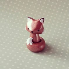 a small red fox figurine sitting on top of a polka dot tablecloth