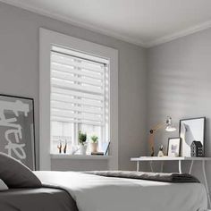 a white bed sitting in a bedroom next to a window with blinds on the windowsill