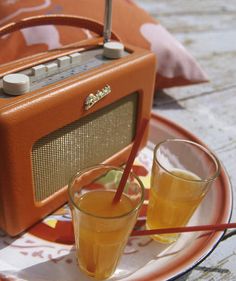 an orange radio sitting on top of a plate next to two glasses filled with liquid