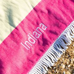 a pink and white towel with the word india on it sitting on top of some dirt