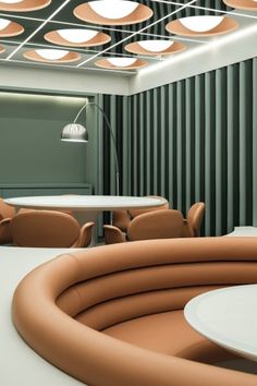 an empty meeting room with round tables, chairs and circular lights on the ceiling above