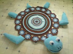 a crocheted blue and brown rug with two stuffed animals on it