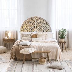 a bedroom with white walls and wooden flooring has a large round headboard above the bed