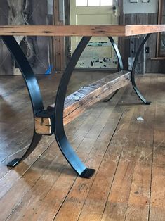 a wooden bench sitting on top of a hard wood floor next to a wall with windows