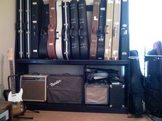 guitar cases and amps are lined up on a shelf in a room with windows