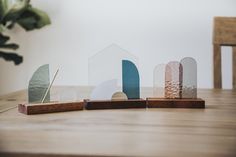 three small wooden houses sitting on top of a table next to a potted plant