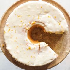 a frosted donut with a bite taken out of it on a wooden plate