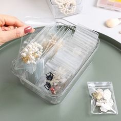 a plastic container filled with lots of different types of buttons and pins on top of a table