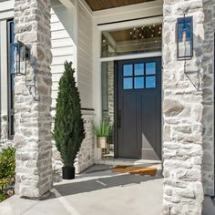 the front entrance to a house with two potted plants on each side and an entry door