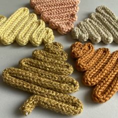 several knitted objects are arranged on a table top, one is yellow and the other is brown