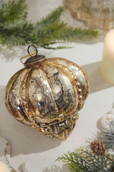 an ornament is sitting on a table next to candles and pine branches,